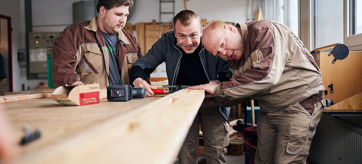 Drei Männer in der Holzwerkstatt. 