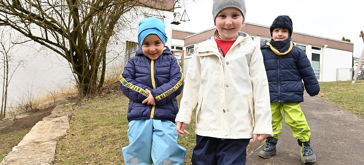 Drei kleine Kinder in Winterkleidung.